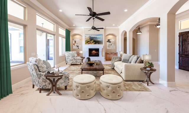 living area featuring marble finish floor, recessed lighting, a lit fireplace, crown molding, and baseboards