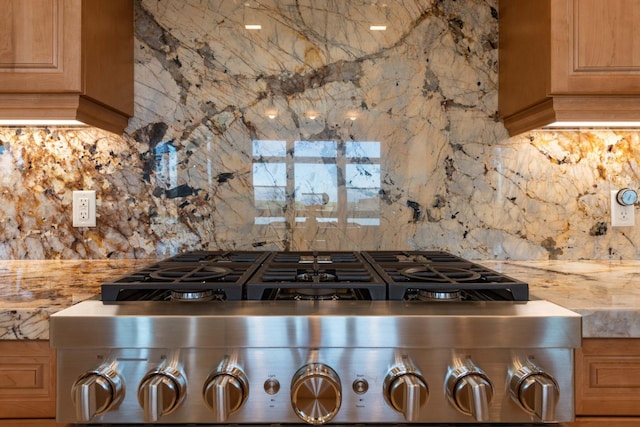 kitchen with stove, light brown cabinets, tasteful backsplash, and light countertops