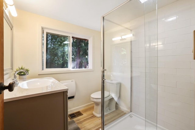 bathroom featuring vanity, hardwood / wood-style flooring, toilet, and a shower with door