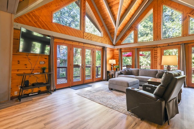 living room with beam ceiling, a healthy amount of sunlight, high vaulted ceiling, and light hardwood / wood-style flooring