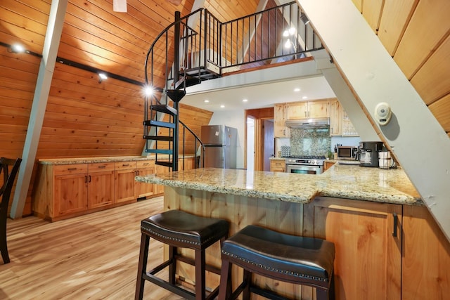 kitchen featuring backsplash, light wood-type flooring, a towering ceiling, kitchen peninsula, and stainless steel appliances