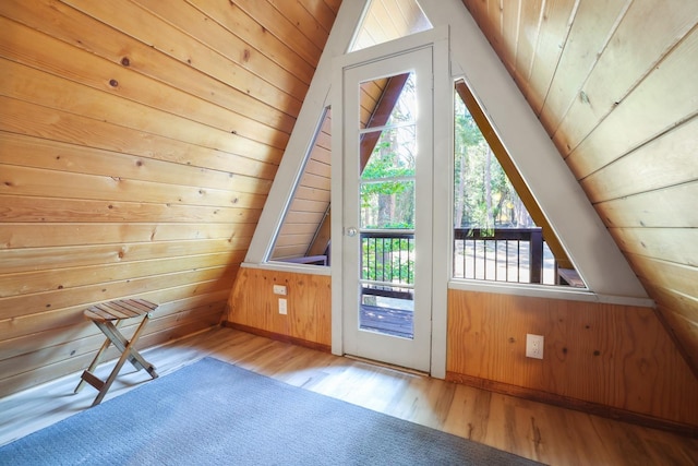 additional living space with light wood-type flooring, wooden ceiling, vaulted ceiling, and wooden walls