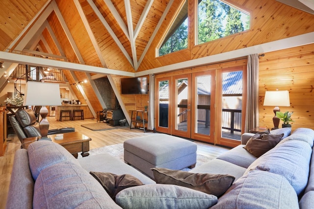 living room with a wood stove, wooden ceiling, beamed ceiling, wood walls, and light hardwood / wood-style floors