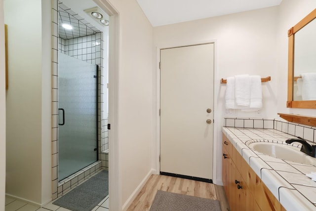 bathroom with hardwood / wood-style floors, vanity, and a shower with door