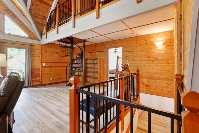 hall with wooden walls, wood-type flooring, and vaulted ceiling