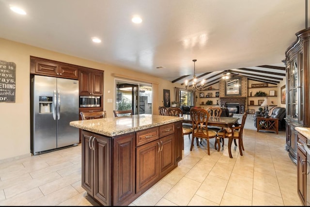 kitchen featuring vaulted ceiling with beams, open floor plan, appliances with stainless steel finishes, a center island, and pendant lighting