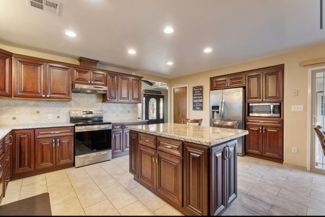 kitchen with visible vents, a kitchen island, light stone countertops, stainless steel appliances, and under cabinet range hood