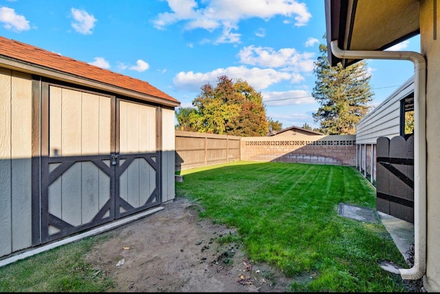 view of yard featuring a fenced backyard, a storage unit, and an outdoor structure