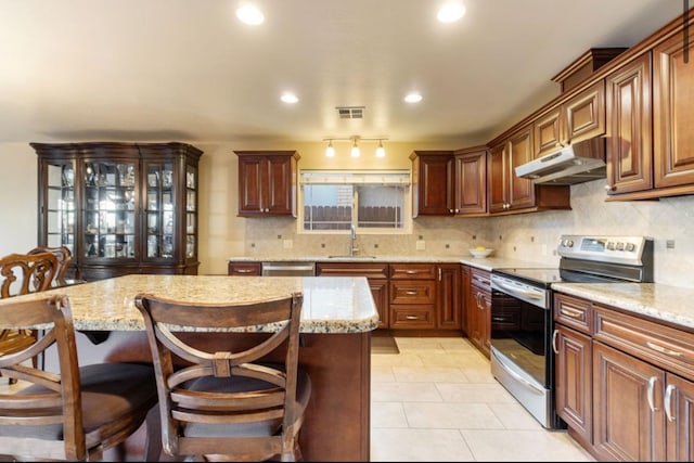 kitchen with visible vents, stainless steel range with electric cooktop, a kitchen island, a sink, and under cabinet range hood