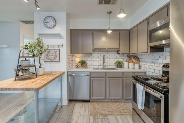 kitchen featuring decorative light fixtures, sink, stainless steel appliances, and tasteful backsplash