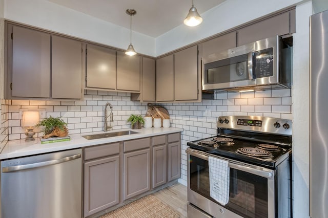 kitchen with tasteful backsplash, sink, hanging light fixtures, and appliances with stainless steel finishes