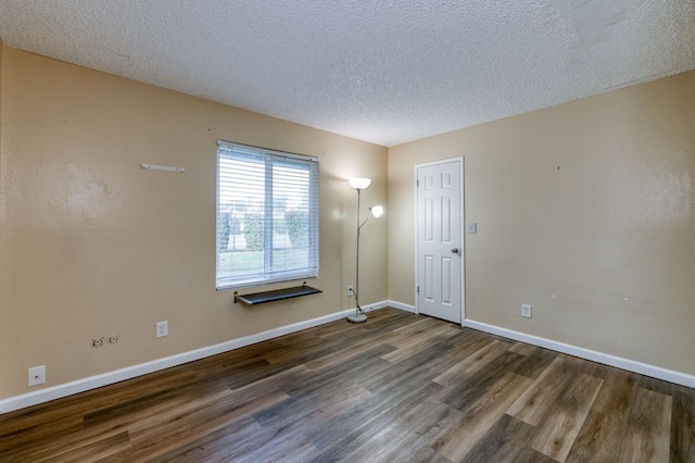 spare room featuring dark hardwood / wood-style flooring and a textured ceiling