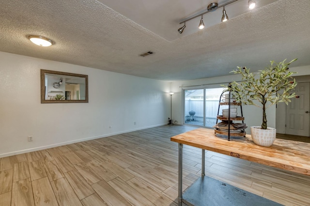 interior space featuring hardwood / wood-style flooring, a textured ceiling, and track lighting