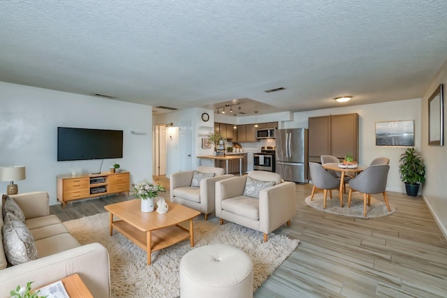 living room featuring a textured ceiling and light hardwood / wood-style flooring