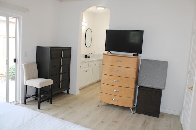 bedroom featuring ensuite bath, light hardwood / wood-style flooring, and sink