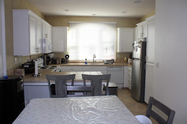 kitchen featuring tile countertops, white cabinetry, white appliances, and sink