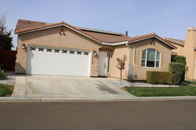 mediterranean / spanish-style house featuring a garage and solar panels