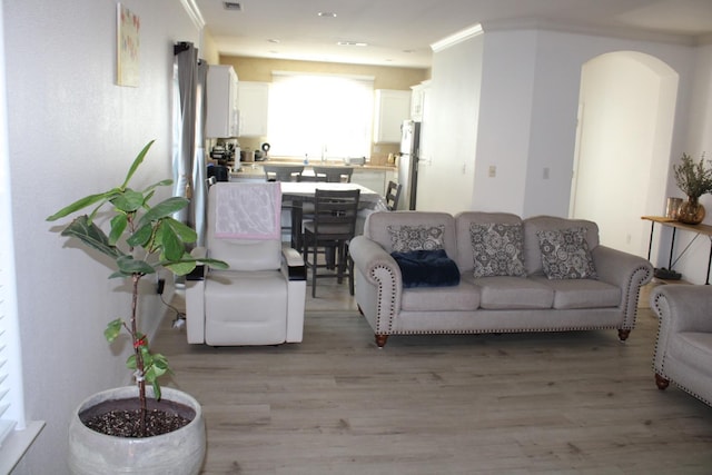 living room featuring light wood-type flooring and ornamental molding