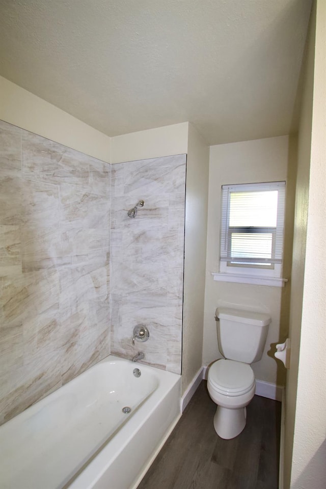 bathroom featuring hardwood / wood-style floors, tiled shower / bath combo, and toilet