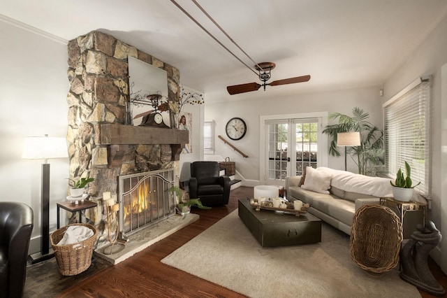 living room featuring crown molding, ceiling fan, a fireplace, and dark wood-type flooring