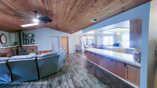 living room featuring lofted ceiling, a wood stove, wooden ceiling, ceiling fan with notable chandelier, and dark hardwood / wood-style flooring