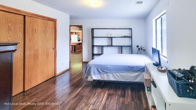 bedroom featuring a textured ceiling, dark hardwood / wood-style flooring, white fridge, and a closet