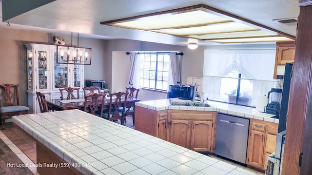 kitchen featuring a notable chandelier, tile counters, a healthy amount of sunlight, and dishwasher