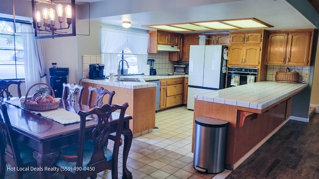 kitchen with tile countertops, sink, oven, and white fridge