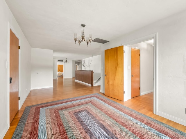 spare room featuring a chandelier and light hardwood / wood-style flooring