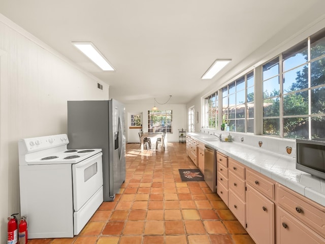 kitchen with white cabinets, sink, light tile patterned floors, tile counters, and stainless steel appliances