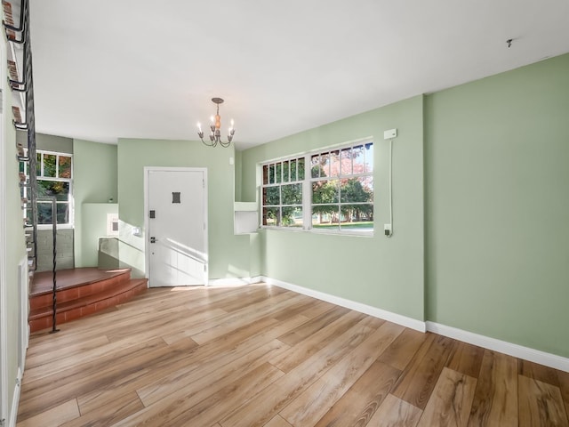 unfurnished room featuring light wood-type flooring and an inviting chandelier