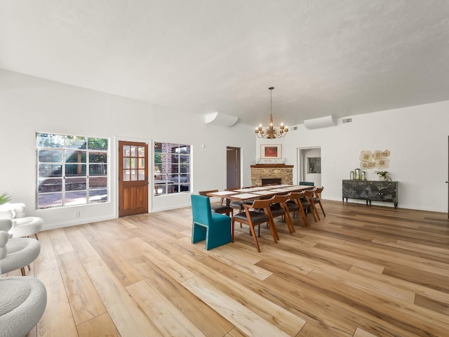 dining space with a fireplace, light hardwood / wood-style floors, and a notable chandelier