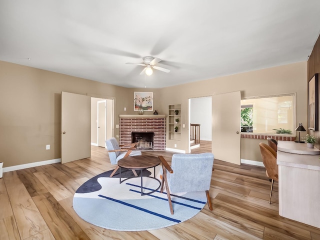 living room featuring ceiling fan, a fireplace, and light hardwood / wood-style floors