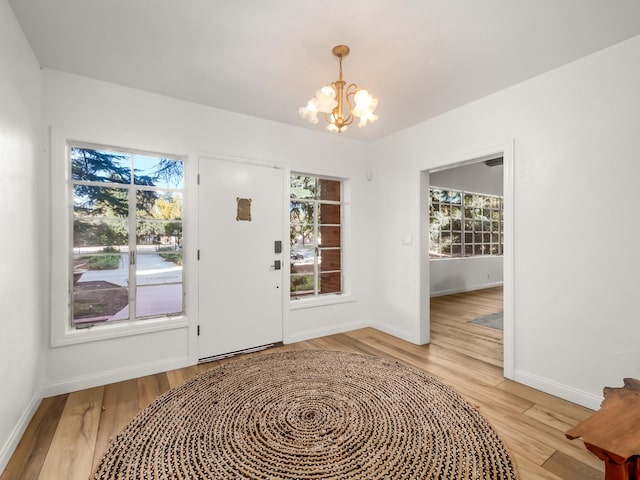 doorway with light hardwood / wood-style floors, a wealth of natural light, and an inviting chandelier