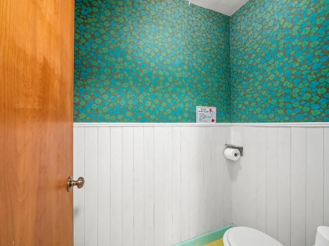 bathroom featuring toilet and wooden walls