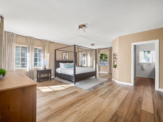 unfurnished bedroom featuring a walk in closet, multiple windows, and light hardwood / wood-style flooring