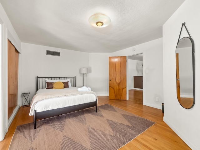 bedroom with wood-type flooring and a textured ceiling