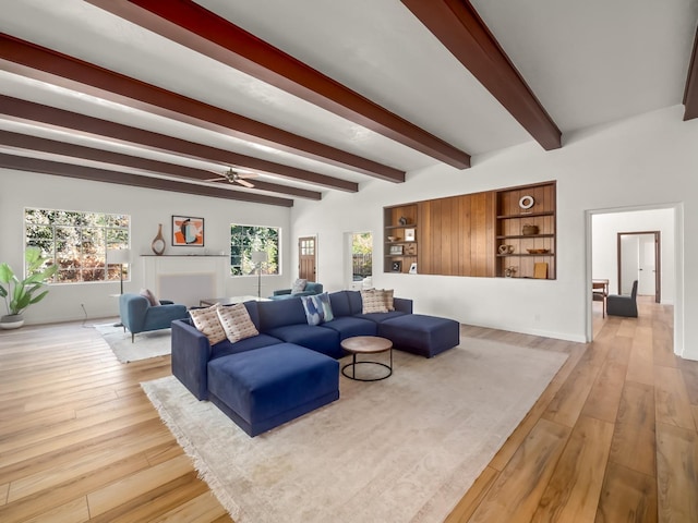 living room with beamed ceiling, ceiling fan, and light wood-type flooring