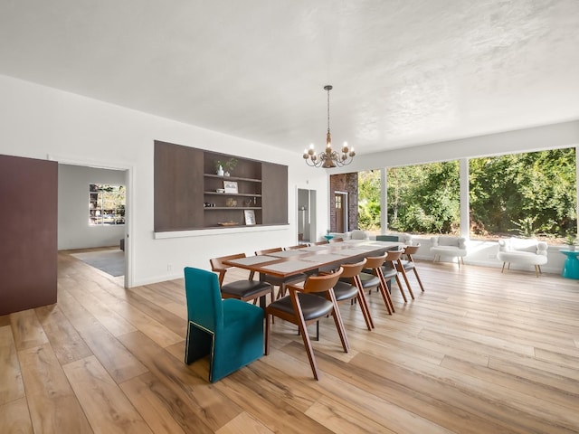 dining area with light hardwood / wood-style flooring, built in features, and a notable chandelier