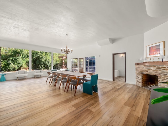 dining space with a fireplace, light wood-type flooring, and a notable chandelier