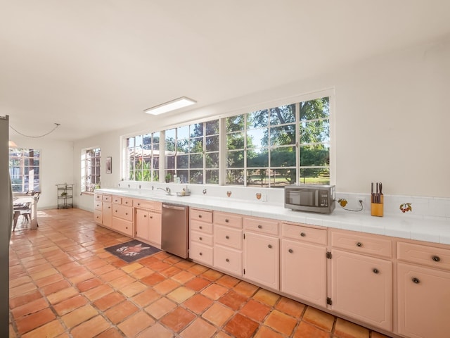 kitchen featuring tile countertops, sink, light tile patterned floors, and appliances with stainless steel finishes