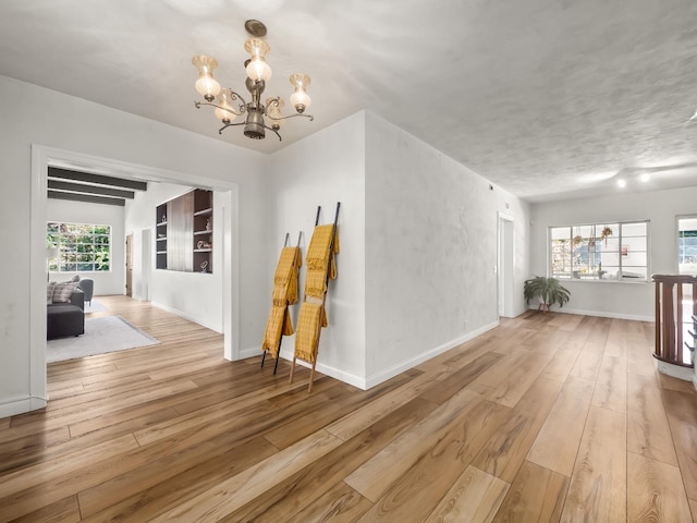 corridor featuring plenty of natural light, a chandelier, and light wood-type flooring