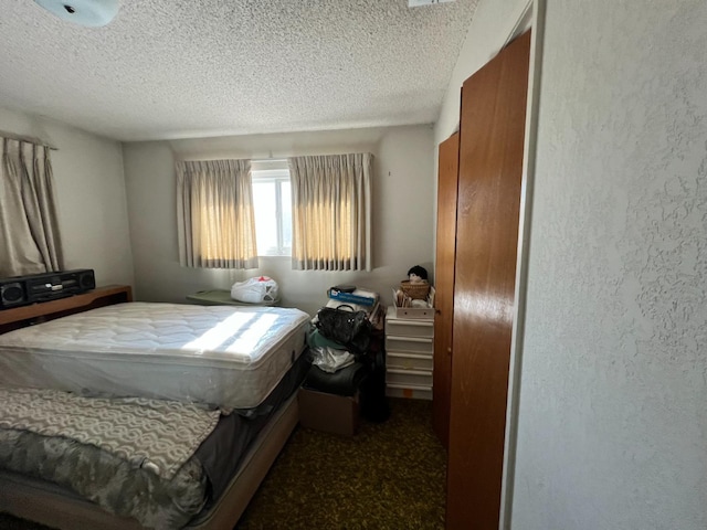 bedroom featuring a textured ceiling and dark carpet