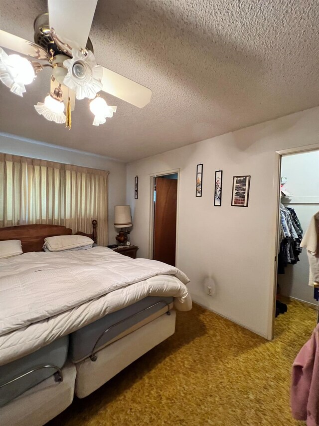 bedroom with ceiling fan, carpet floors, a textured ceiling, a walk in closet, and a closet