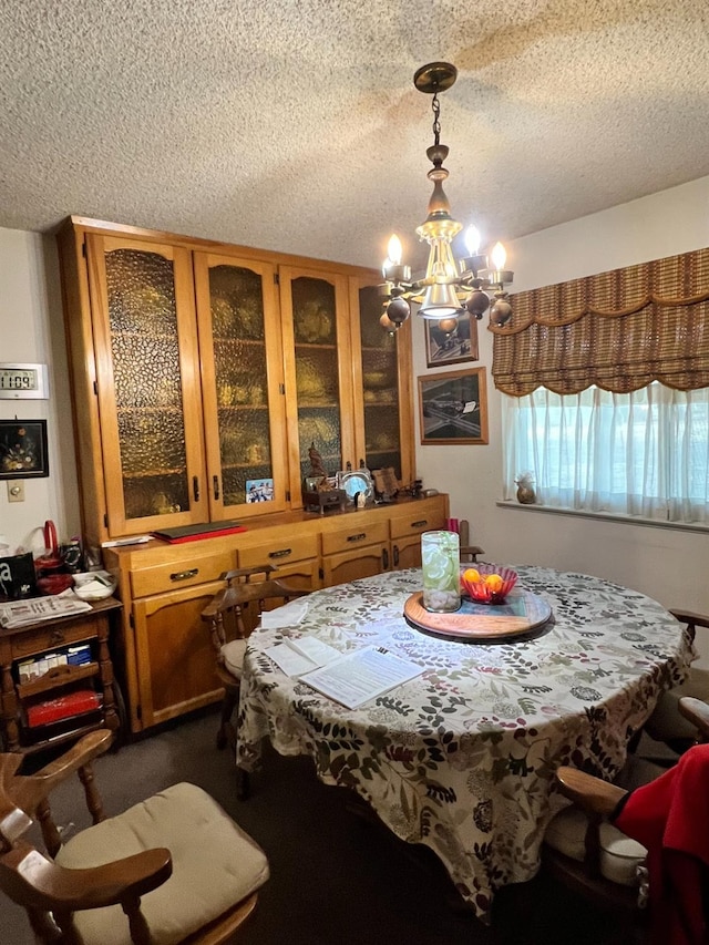 dining room featuring a chandelier, a textured ceiling, and dark carpet