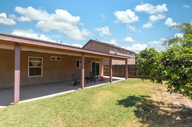 rear view of house featuring a lawn and a patio