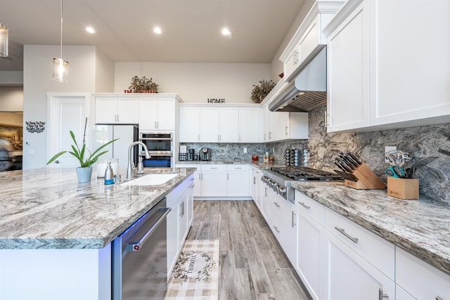 kitchen featuring under cabinet range hood, appliances with stainless steel finishes, white cabinets, and a sink