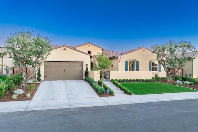 mediterranean / spanish house featuring a tile roof, stucco siding, a garage, driveway, and a front lawn