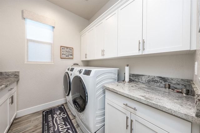 laundry area with light wood-type flooring, washing machine and dryer, cabinet space, and baseboards