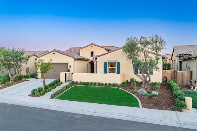 mediterranean / spanish-style home featuring stucco siding, concrete driveway, fence, a garage, and a tiled roof